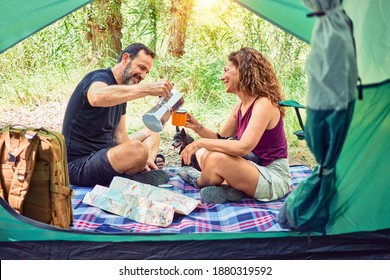 Middle Age Couple  Of Hiker Smiling Happy Drinking Coffee Camping At The Forest.