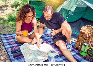 Middle Age Couple  Of Hiker Smiling Happy Drinking Coffee. Looking At The Map Camping At The Forest