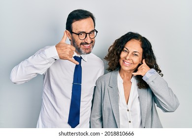 Middle Age Couple Of Hispanic Woman And Man Wearing Business Office Uniform Smiling Doing Phone Gesture With Hand And Fingers Like Talking On The Telephone. Communicating Concepts. 