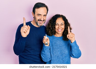 Middle Age Couple Of Hispanic Woman And Man Holding Keys Of New Home Pointing Finger Up With Successful Idea. Exited And Happy. Number One. 