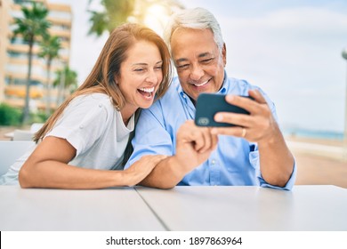 Middle age couple in love sitting at the terrace of coffee shop using smartphone happy and cheerful together - Powered by Shutterstock