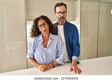 Middle Age Couple Standing Together In Shock Face, Looking Skeptical And Sarcastic, Surprised With Open Mouth 