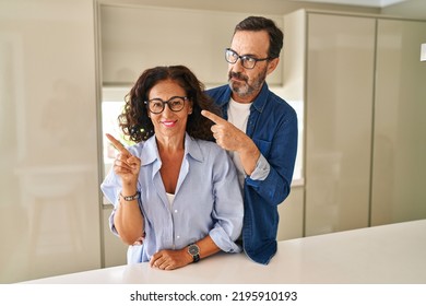 Middle Age Couple Standing Together Pointing With Hand Finger To The Side Showing Advertisement, Serious And Calm Face 