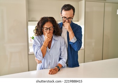 Middle age couple standing together feeling unwell and coughing as symptom for cold or bronchitis. health care concept. 
