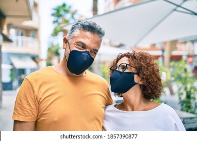 Middle Age Couple Wearing Coronavirus Protection Mask Walking At Street Of City.