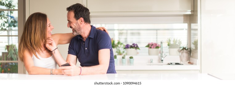 Middle age couple, woman and man using smartphone at kitchen. Ultra wide home shot. - Powered by Shutterstock