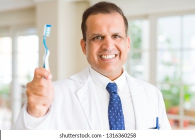 Middle age dentist man holding toothbrush and smiling - Powered by Shutterstock