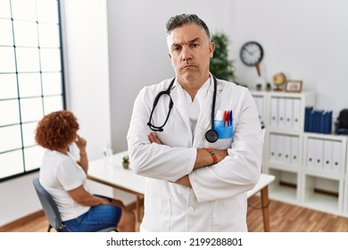 Middle age doctor man at the clinic with a patient skeptic and nervous, disapproving expression on face with crossed arms. negative person. 