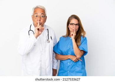 Middle age doctor and nurse isolated on white background showing a sign of silence gesture putting finger in mouth