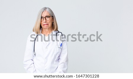 middle age doctor woman looking goofy and funny with a silly cross-eyed expression, joking and fooling around