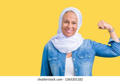 Middle age eastern arab woman wearing arabian hijab over isolated background Strong person showing arm muscle, confident and proud of power