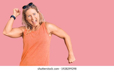 Middle age fit blonde woman wearing casual summer clothes and sunglasses dancing happy and cheerful, smiling moving casual and confident listening to music  - Powered by Shutterstock