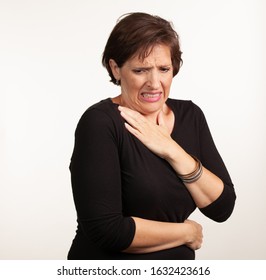 Middle Age Gen X Caucasian Woman In Black On A White Background Making A Painful Or Upset Expresison. Unwell Painful Concept.