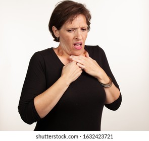 Middle Age Gen X Caucasian Woman In Black On A White Background Making A Painful Or Upset Expresison. Unwell Painful Concept.