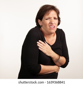 Middle Age Gen X Caucasian Woman In Black On A White Background Making A Painful Or Upset Expresison. Unwell Painful Concept.