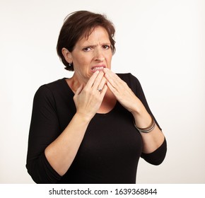 Middle Age Gen X Caucasian Woman In Black On A White Background Making A Painful Or Upset Expresison. Unwell Painful Concept.