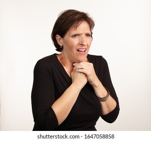 Middle Age Gen X Caucasian Woman In Black On A White Background Making A Painful Or Upset Expresison. Unwell Painful Concept.