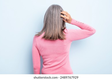 middle age gray hair woman feeling clueless and confused, thinking a solution, with hand on hip and other on head, rear view - Powered by Shutterstock