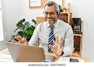 Middle age grey-haired man call center agent smiling confident working at office - Powered by Shutterstock