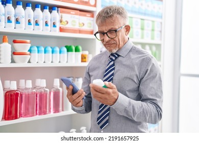 Middle Age Grey-haired Man Customer Using Smartphone Holding Medicine Bottle At Laboratory