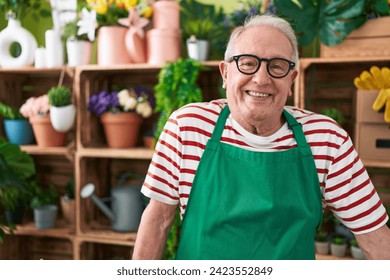 Middle age grey-haired man florist smiling confident standing at flower shop - Powered by Shutterstock