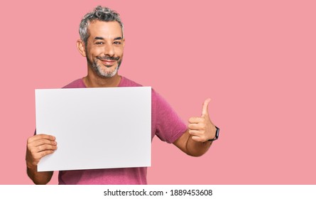 Middle Age Grey-haired Man Holding Blank Empty Banner Smiling Happy And Positive, Thumb Up Doing Excellent And Approval Sign 