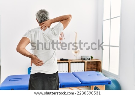 Middle age grey-haired man patient suffering for backache standing at rehab clinic
