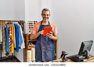 Middle age grey-haired man shop assistant using touchpad at clothing store - Powered by Shutterstock