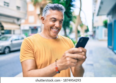 Middle age grey-haired man smiling happy using smartphone walking at street of city. - Powered by Shutterstock