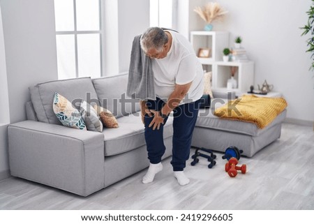 Middle age grey-haired man suffering for knee injury at street