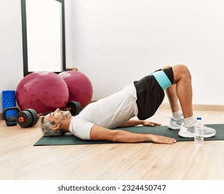 Middle age grey-haired man training leg exercise at sport center - Powered by Shutterstock