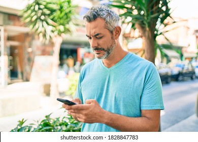 Middle Age Grey-haired Man Using Smartphone At Street Of City Thinking Attitude And Sober Expression Looking Self Confident 