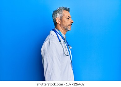 Middle Age Grey-haired Man Wearing Doctor Uniform And Stethoscope Looking To Side, Relax Profile Pose With Natural Face With Confident Smile. 