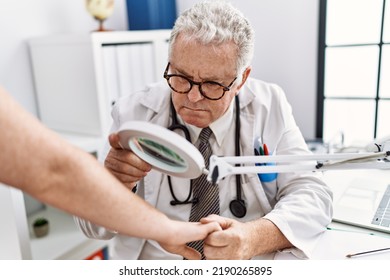 Middle Age Grey-haired Man Wearing Dermatologist Uniform Examining Skin Arm Using Loupe At Dermatology Clinic