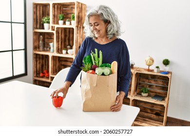 Middle Age Grey-haired Woman Holding Paper Bag With Groceries Standing At Home.