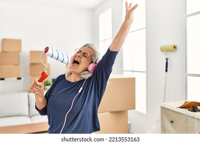 Middle Age Grey-haired Woman Listening To Music And Singing At New Home.