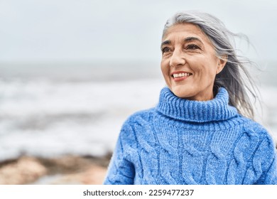 Middle age grey-haired woman smiling confident looking to the side at seaside - Powered by Shutterstock