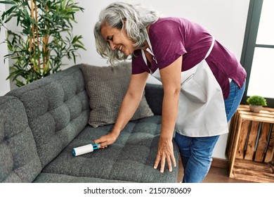 Middle Age Grey-haired Woman Using Pet Hair Remover Roller At Home.