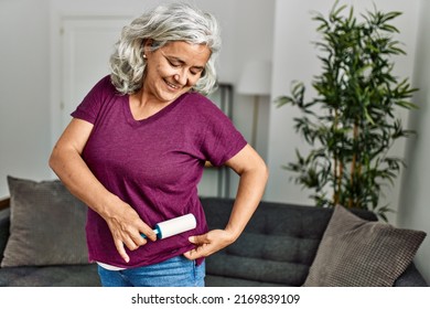 Middle Age Grey-haired Woman Using Pet Hair Remover Roller At Home.