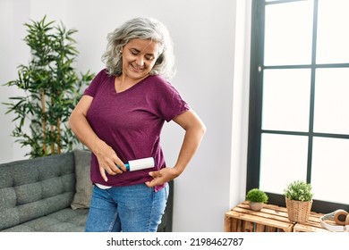 Middle Age Grey-haired Woman Using Pet Hair Remover Roller At Home.