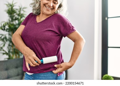 Middle Age Grey-haired Woman Using Pet Hair Remover Roller At Home.