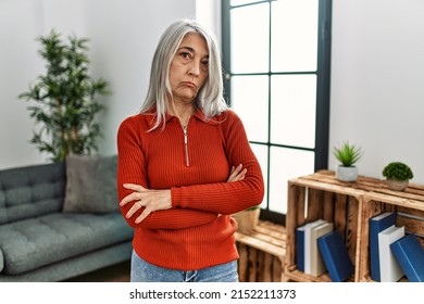 Middle Age Grey-haired Woman Wearing Casual Clothes Standing At Home Skeptic And Nervous, Disapproving Expression On Face With Crossed Arms. Negative Person. 