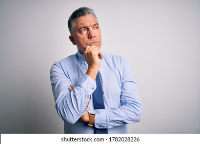 Middle age handsome grey-haired business man wearing elegant shirt and tie with hand on chin thinking about question, pensive expression. Smiling with thoughtful face. Doubt concept.