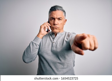 Middle Age Handsome Grey-haired Man Having Conversation Talking On The Smartphone Pointing With Finger To The Camera And To You, Hand Sign, Positive And Confident Gesture From The Front