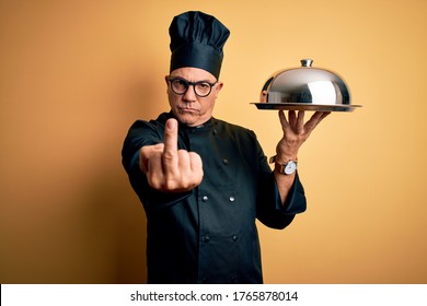 Middle Age Handsome Grey-haired Waiter Man Wearing Cooker Uniform And Hat Holding Tray Showing Middle Finger, Impolite And Rude Fuck Off Expression