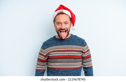 Middle Age Handsome Man With Cheerful And Rebellious Attitude, Joking And Sticking Tongue Out. Christmas Concept