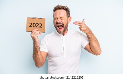 Middle Age Handsome Man Looking Unhappy And Stressed, Suicide Gesture Making Gun Sign. 2022 Calendar Concept