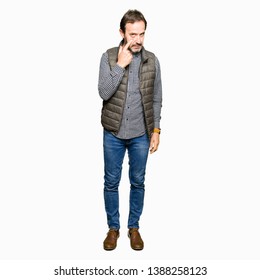 Middle age handsome man wearing winter vest Pointing to the eye watching you gesture, suspicious expression