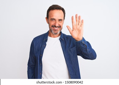 Middle age handsome man wearing blue denim shirt standing over isolated white background Waiving saying hello happy and smiling, friendly welcome gesture