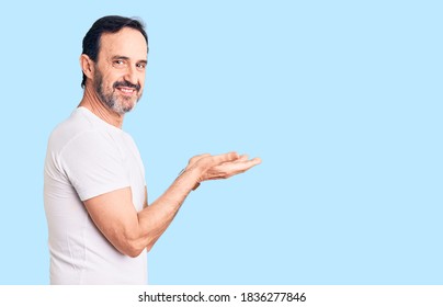 Middle age handsome man wearing casual t-shirt pointing aside with hands open palms showing copy space, presenting advertisement smiling excited happy  - Shutterstock ID 1836277846